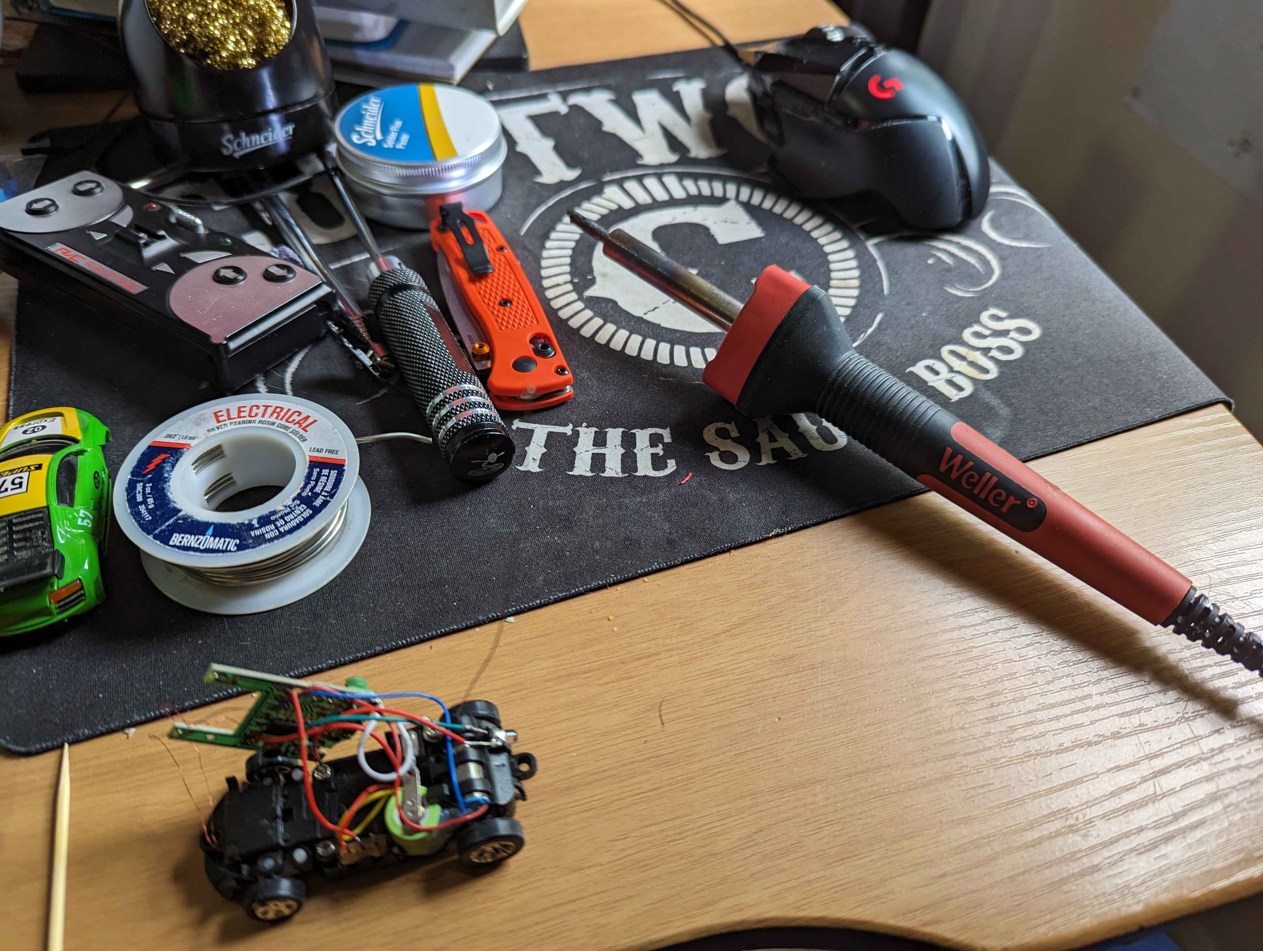 A small RC car disassembled on a desk, with tools