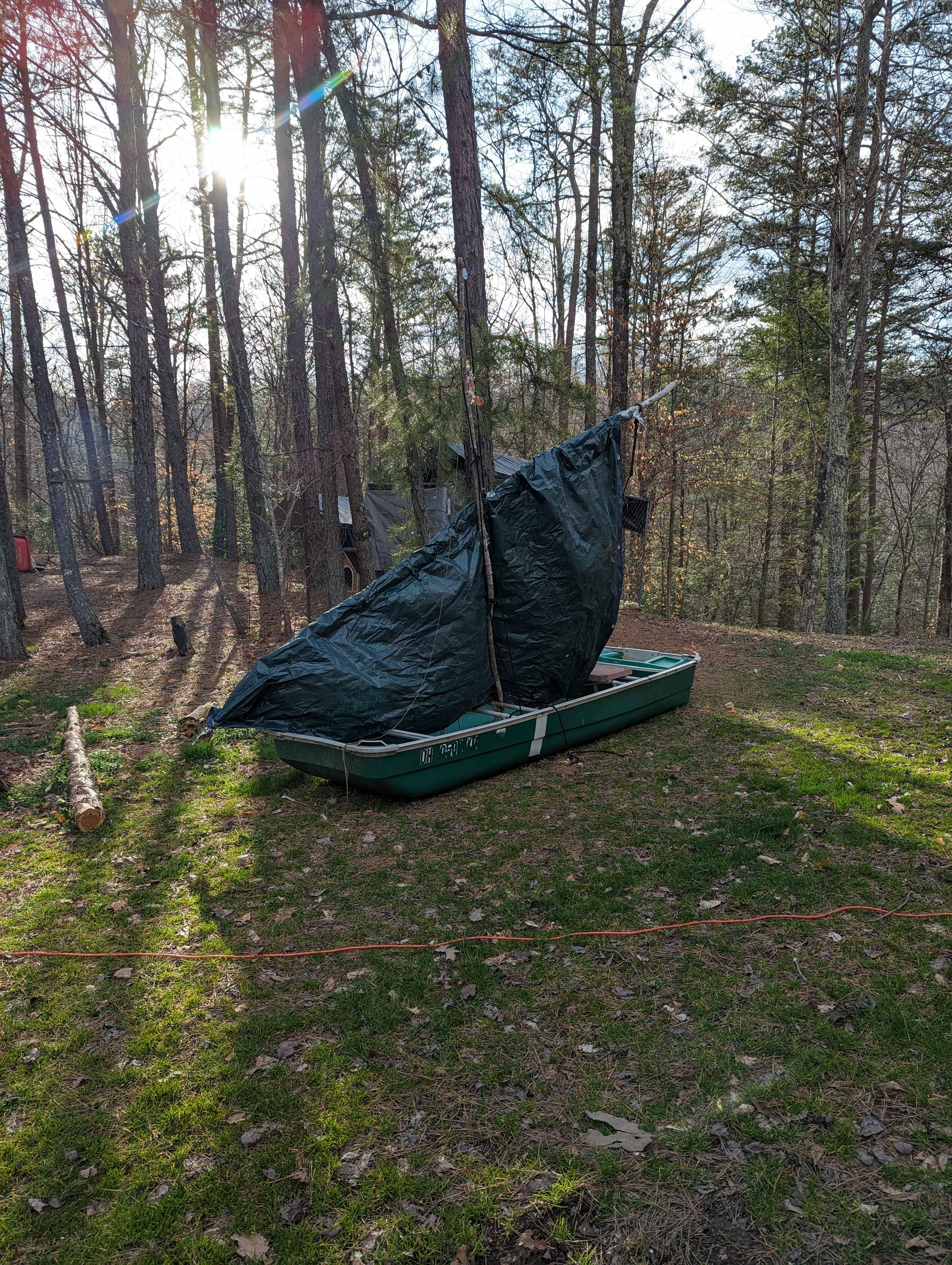A small boat with an improvised sail sitting in some grass